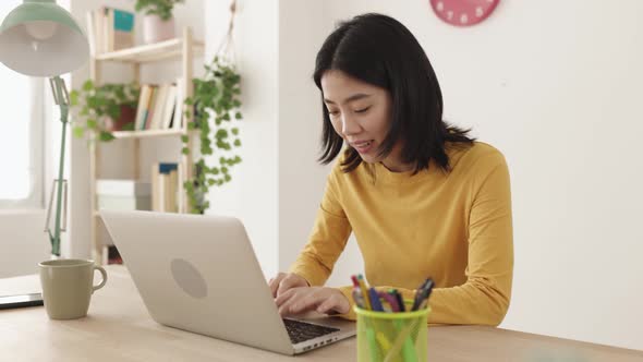 Young Asian Woman Working on Laptop Computer at Home