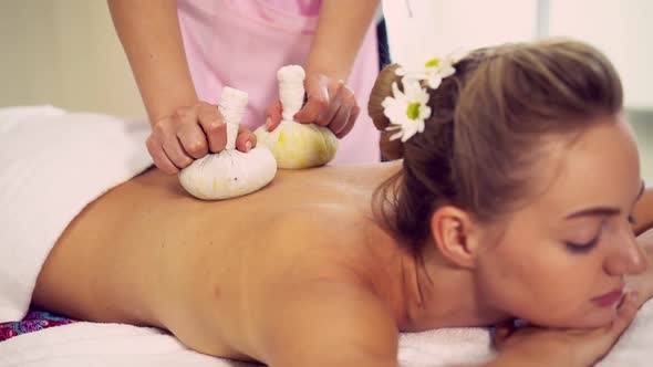 Massage Therapist Using Herbal Compress on Woman