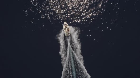 Aerial view of small speed boat with trailing wake on sea.