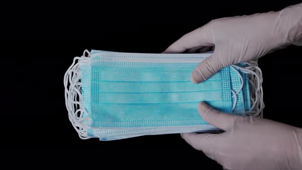 Close Up of Nurse Putting Many Medical Masks on Black Background