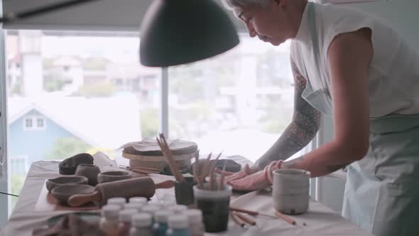 Asian elderly woman enjoying pottery work at home.