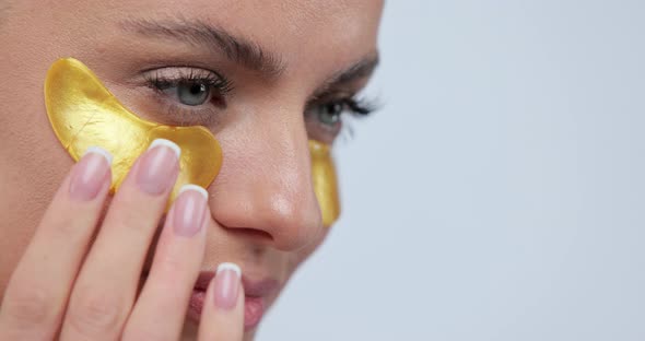 Closeup of Beautiful Smiling Woman in Gold Eye Patches Smiling Over Gray Background