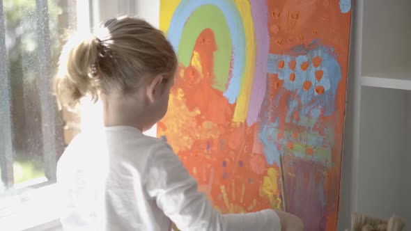 Little girl painting picture with paintbrush