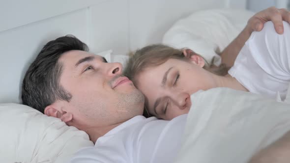 Man Kisses Sleeping Girlfriend in Bed Cuddling