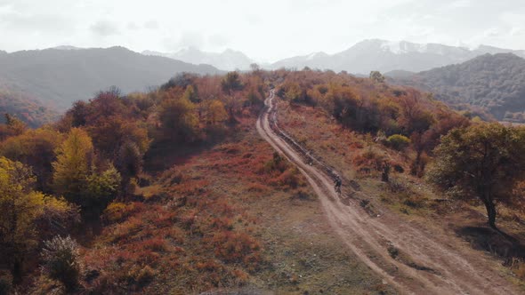 Aerial View of Cyclist in the Mountain Landscape with Autumn Forest