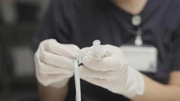 Doctor In Surgical Gloves Preparing Syringe