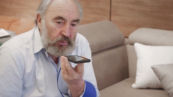 Old man using smart phone voice recognition, dictates thoughts, voice dialing message