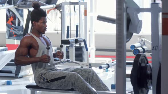 Handsome Athletic African Man Exercising on Seated Low Row Machine at Gym