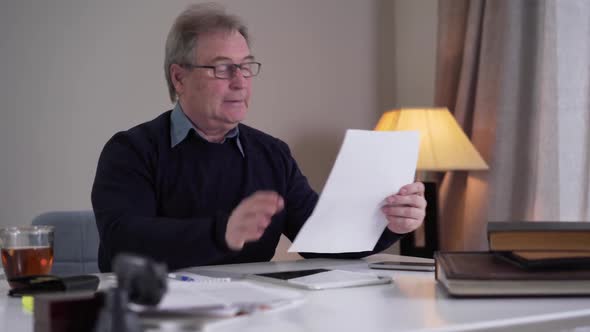 Stressed Mature Caucasian Businessman Comparing Information in Documents and Online and Tearing