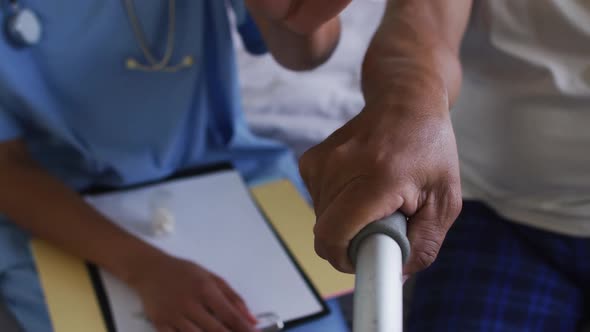 Close up of senior mixed race man with female doctor home visiting holding hands