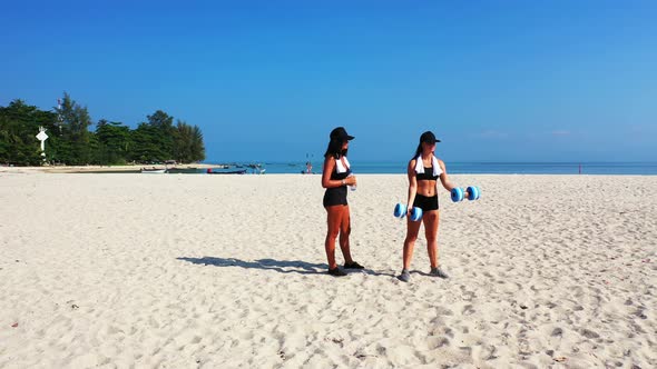 Young smiling ladies relaxing having fun on the beach on paradise white sand and blue 4K background