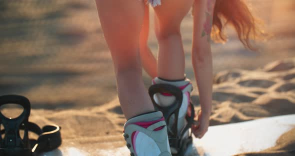 Snowboarder Girl Standing Back Strapping Mounts on Her Snowboard Boots. Female Rider at Dubai Resort