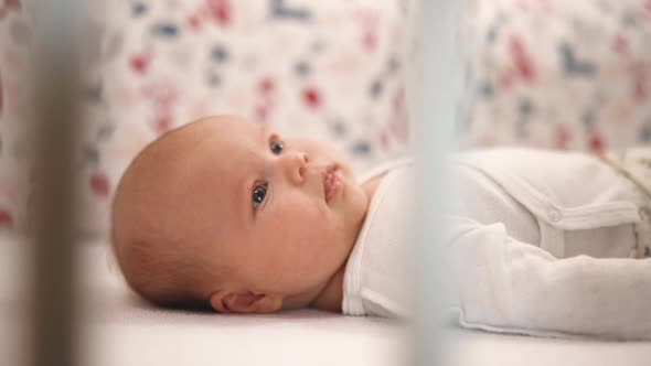 Little Female Toddler Lies in Crib Smiles and Show Tongue