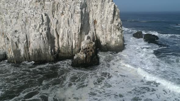 Foamy Waves Crashing Against Rock Formation, Piedra de la Piramide In Chile - aerial drone shot