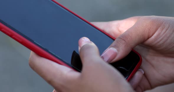 African woman hands holding mobile phone and typing outdoors.