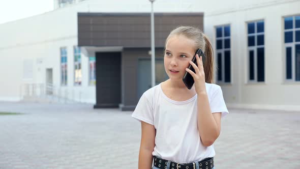 Blonde Girl with Long Hair in Ponytail Talks on Smartphone