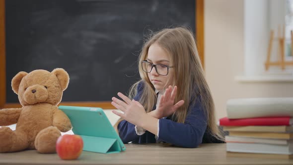 Serious Focused Schoolgirl Gesturing No Crossing Hands Shaking Head Sitting with Tablet at Desk