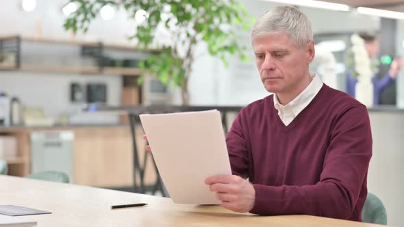 Middle Aged Man Reading Documents at Work