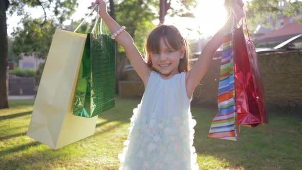 Children Shopping, Small Girl Buyer Rejoices in New Purchases Into Packages and Raises Hands Up at