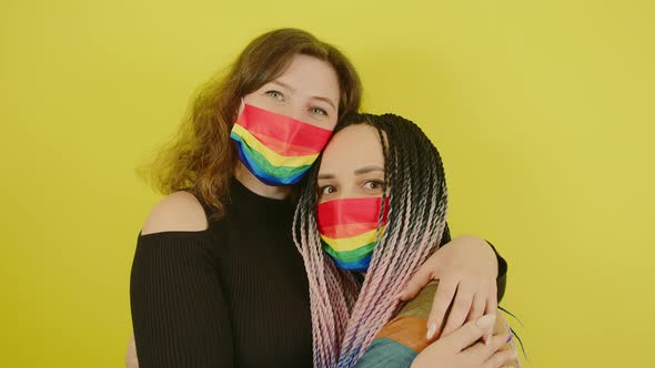 Lesbian Couple in Rainbow Masks Embracing in Studio