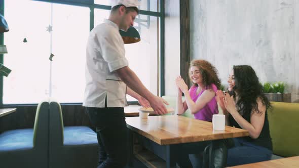 Waiter Bringing Ordered Pizza To Female Friends