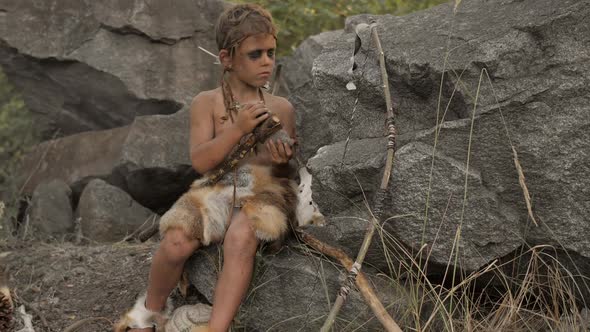 Caveman Manly Boy Making Primitive Stone Weapon in Camp