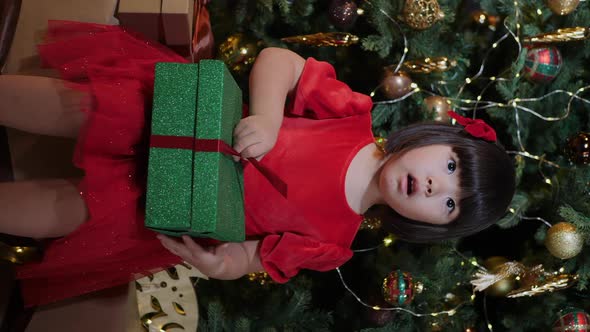 Korean Girl Child is Sitting the Christmas Tree and Opens Gift Green Box