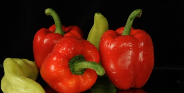 Red And Green Peppers Rotating On Black