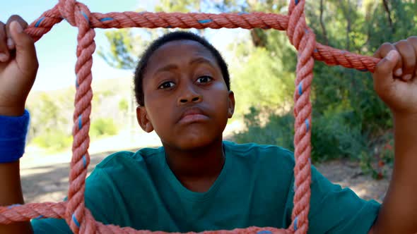 Tired boy leaning on net during obstacle course