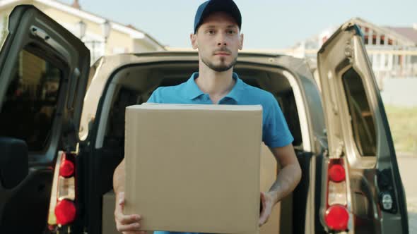 Dolly Shot of Deliveryman Carrying Parcel From Van Then Knocking on Front Door