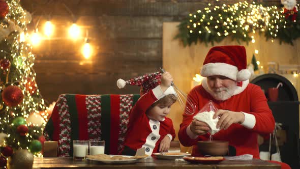 Kid and Santa Claus Enjoying in Served Gingerbread Cake. Santa Grandfather and Grandson Having Fun