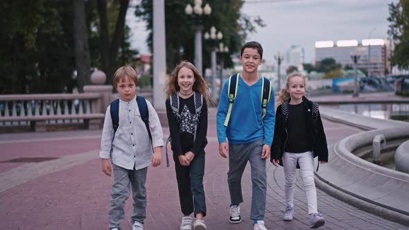 Long Shot of Four Pupils with Backpacks Going Out of School and Talking