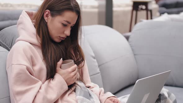 Bad Looking Woman Is Checking Something in a Laptop Sitting on a Couch