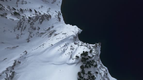 High angle drone video of snow-covered shores of Crater Lake, Oregon, USA