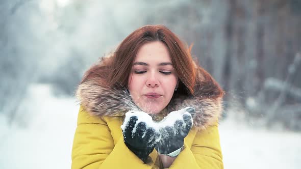 Young Girl Walking in the Woods, Blowing a Handful of Snow on Camera