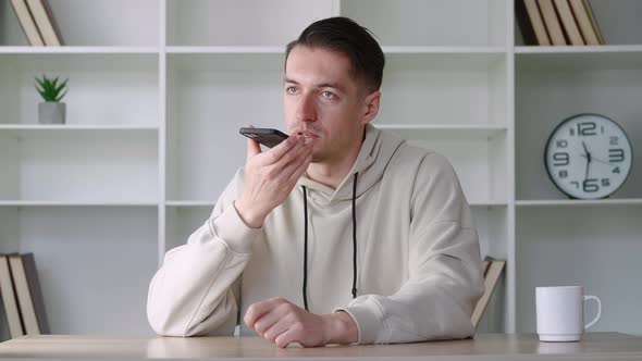 Smiling Young Man Recording Audio Message on Mobile Phone Sending Voice Mail