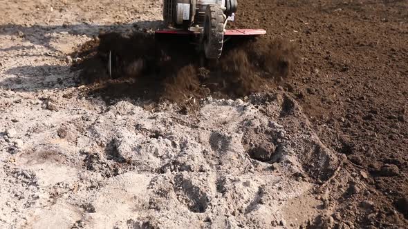 Senior Man Farmer working in the garden plows with Garden Tiller