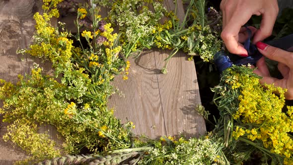 Women's Hands Weave a Wreath of Wildflowers