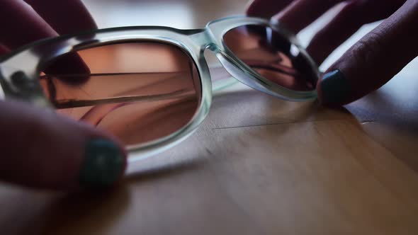 Transparent blue sunglasses being set on light wood table