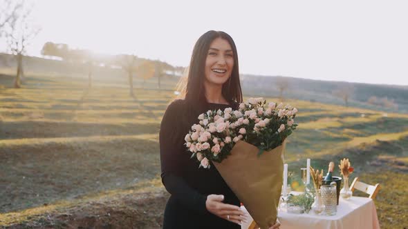 The Portrait of a Charismatic Young Woman in Nature Holding a Bouquet of Beautiful Flowers in Her