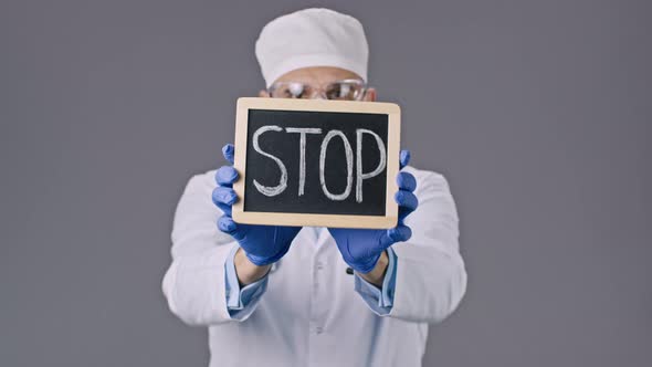 Lab Technician in Protective Mask Holding Tablet with Stop Sign in Hands