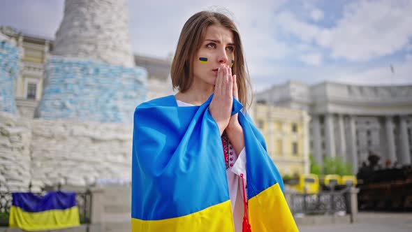 Patriotic Woman Covered with Ukrainian Flag Prays for Peace