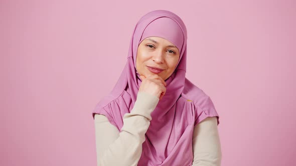 Thoughtful Middle Aged Islamic Woman Looking at Camera with Evaluation and Pointing Gotcha Pink