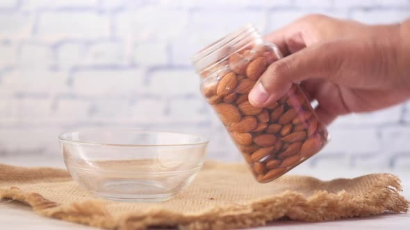Pouring Almond Nuts in a Bowl on Table