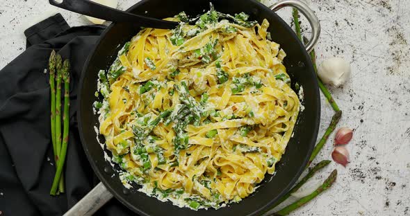 Homemade Tagliatelle Pasta with Ricotta Cheese Creamy Sauce and Fresh Asparagus Served on a Iron Pan