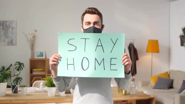 Man in Face Mask Holding Sign Stay Home