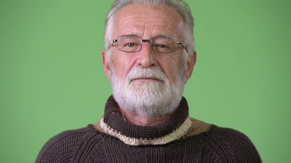 Handsome Senior Bearded Man Wearing Warm Clothing Against Green Background