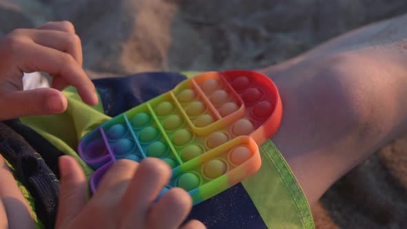 Child Playing with a Rainbow Pop It Presses Bubbles