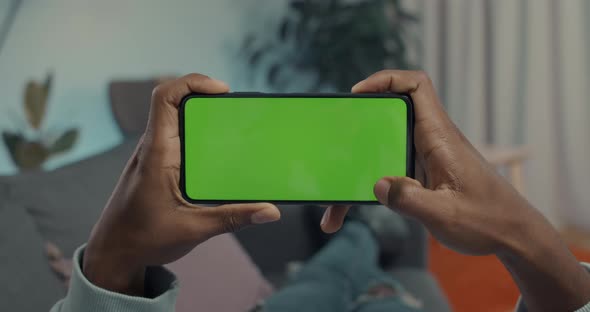 African American Man Scrolling on Green Mock Up Screen of Smartphone