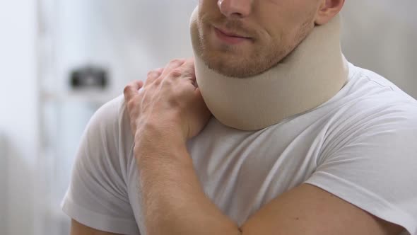 Male in Foam Cervical Collar Massaging Painful Shoulder and Neck, Trauma